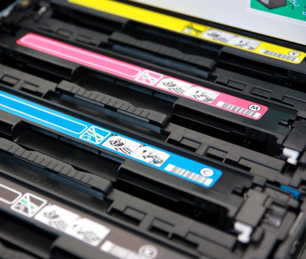 Toner Drei Tonerkartuschen in Schwarz, Cyan, Magenta und Gelb in einem Druckerfach.